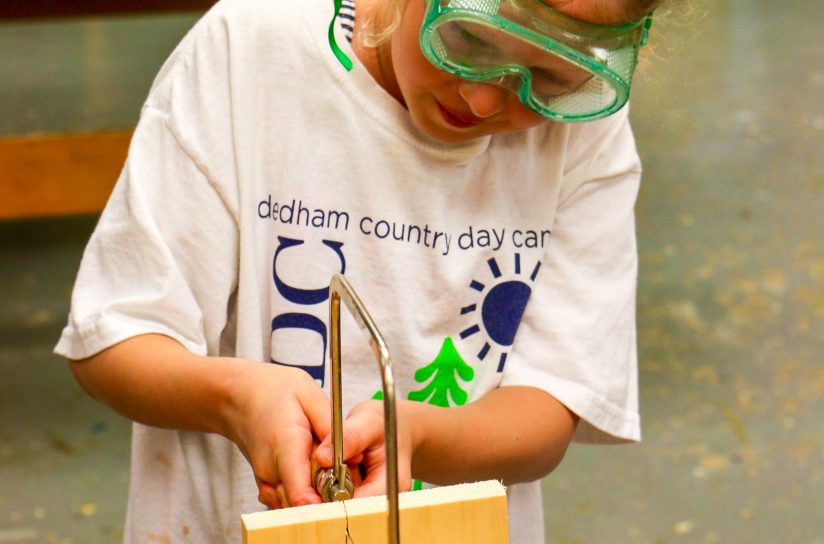 A student using a saw to cut through wood.