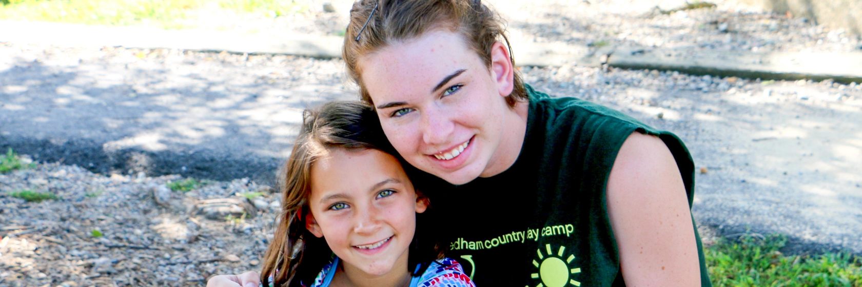 A counselor and a camper posing and smiling for the camera.