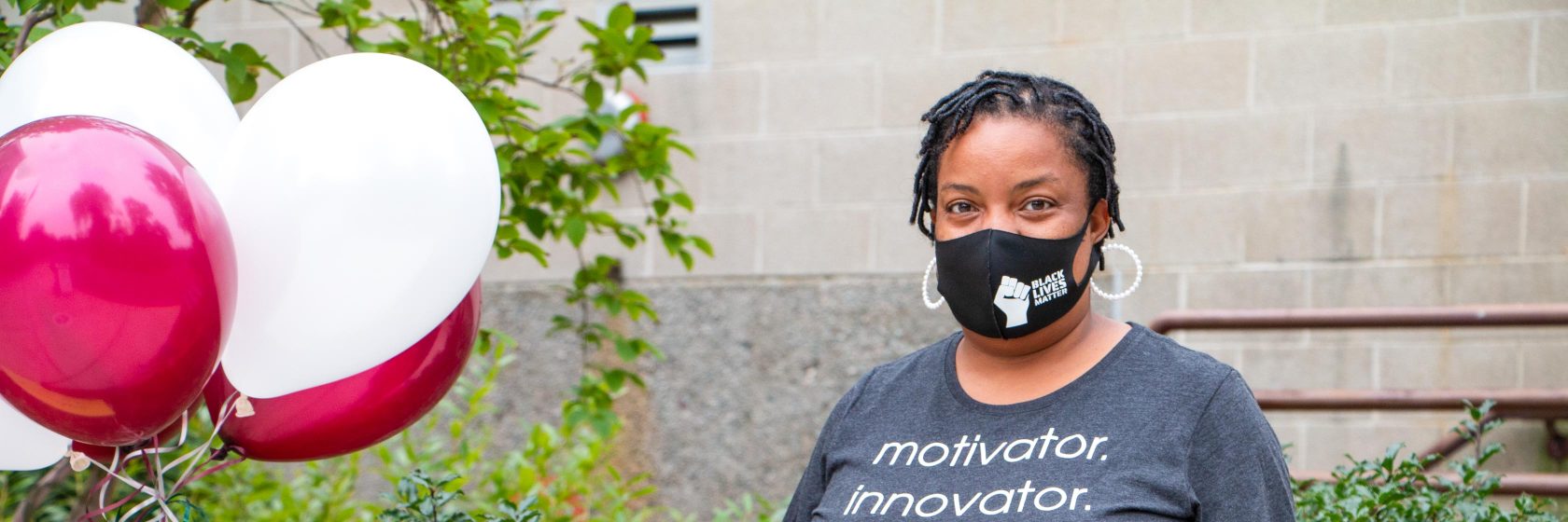 A teacher wearing a mask standing outside the school.