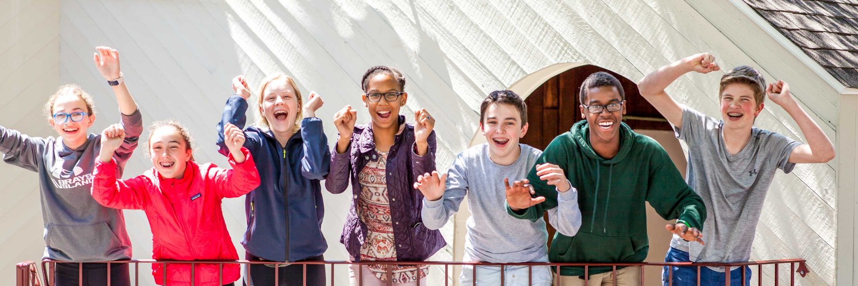 A group of students in a row smiling and cheering.