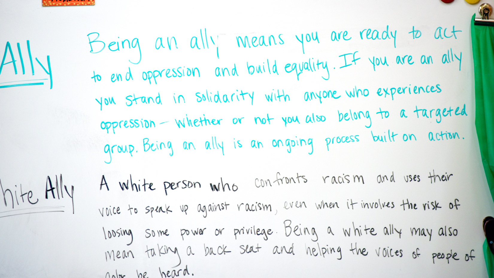 A whiteboard describing the definitions of allyship and white allyship.