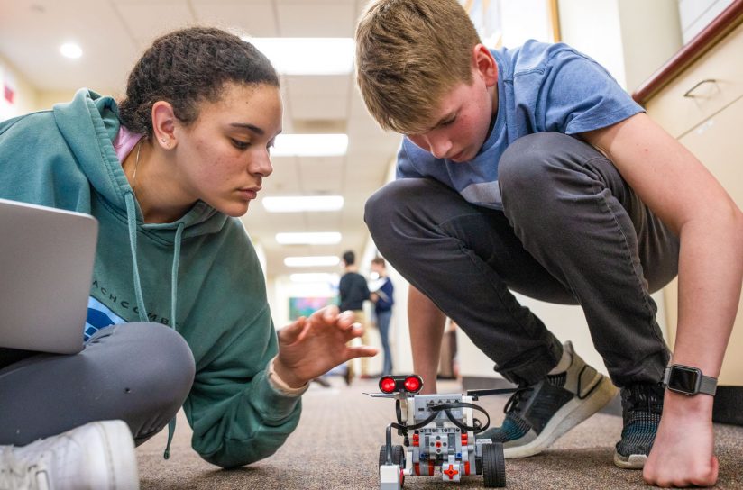 Two students working with a robotic lego car.