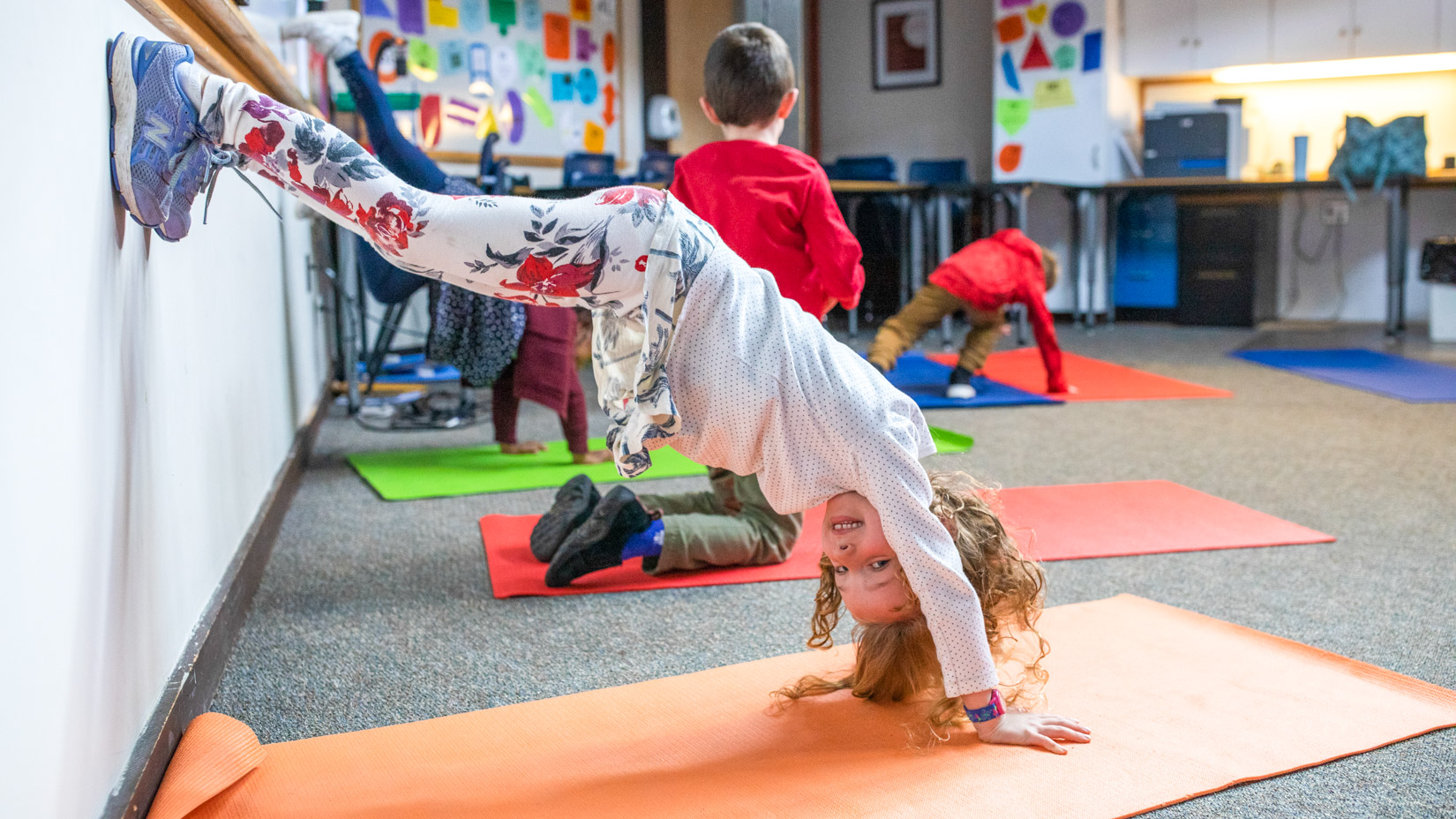 A student stretching upside down on the wall.