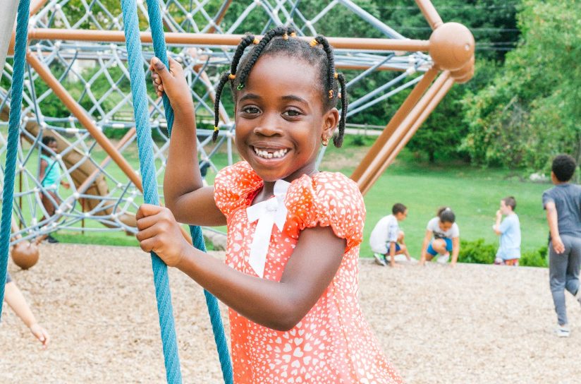 A student smiling while playing on a playground.