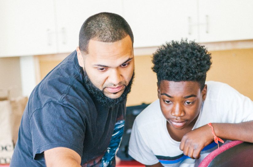 A student and a teacher looking intently at a computer screen.