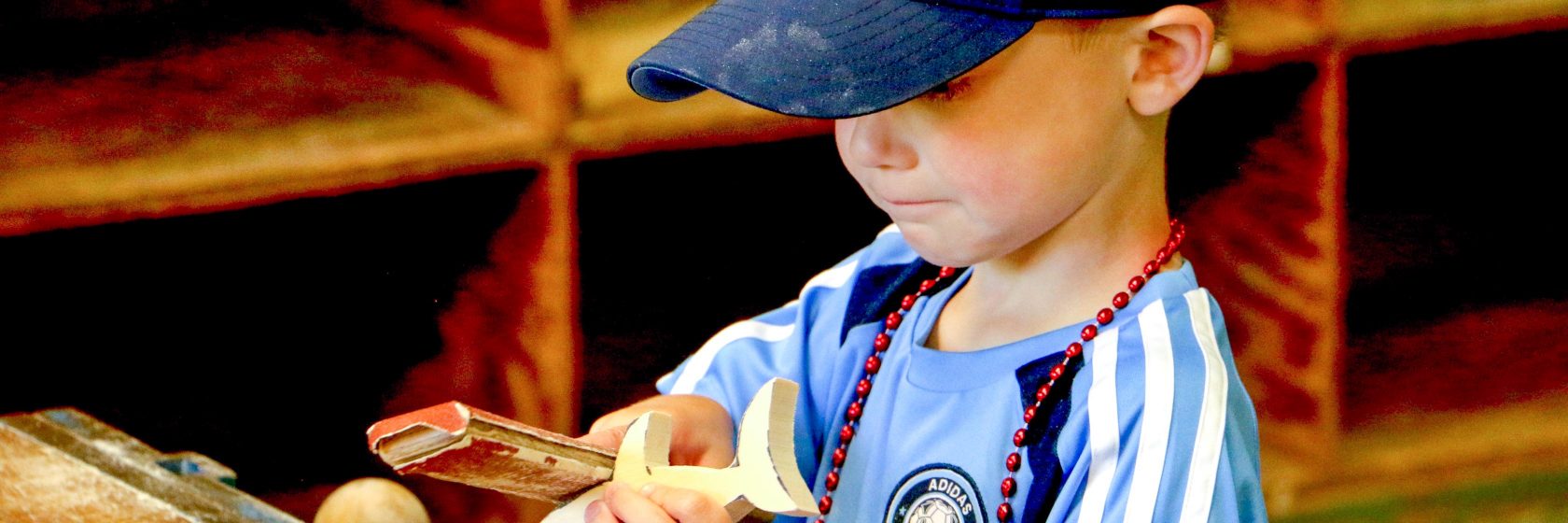 A young camper working on a wooden fish.