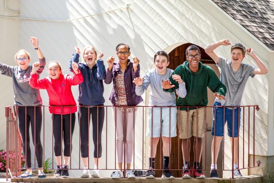 A group of students in a row smiling and cheering.