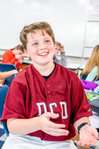 A student explaining something in class and smiling.