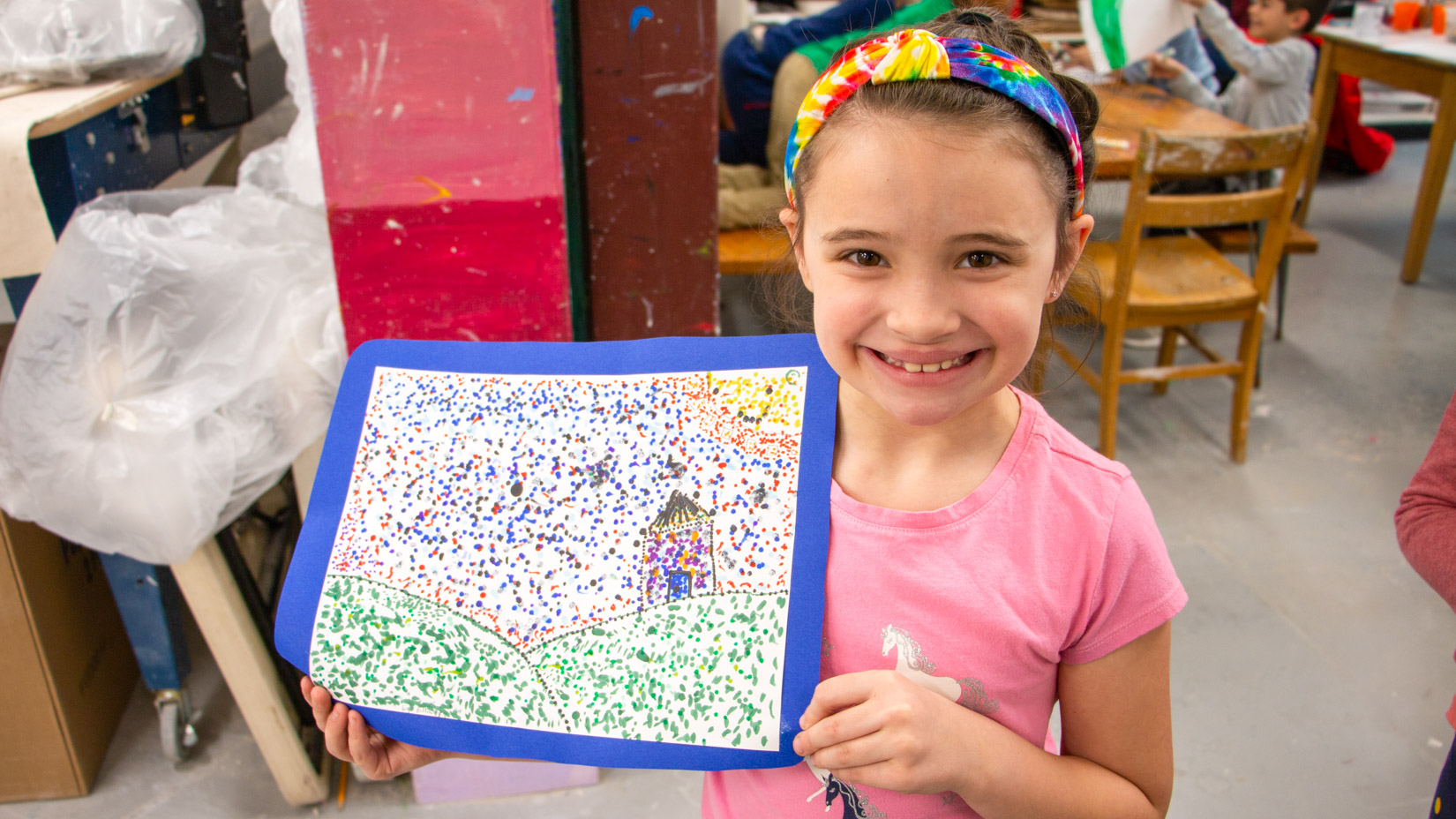 A student smiling with their drawing.