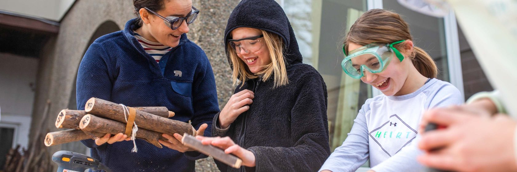 Students working together on a woodworking project and smiling.