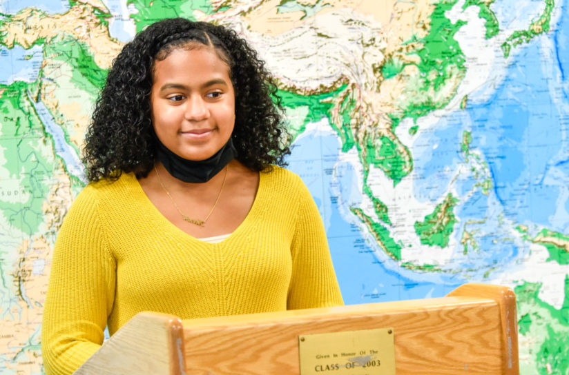 An eighth grader standing at a podium getting ready to speak.