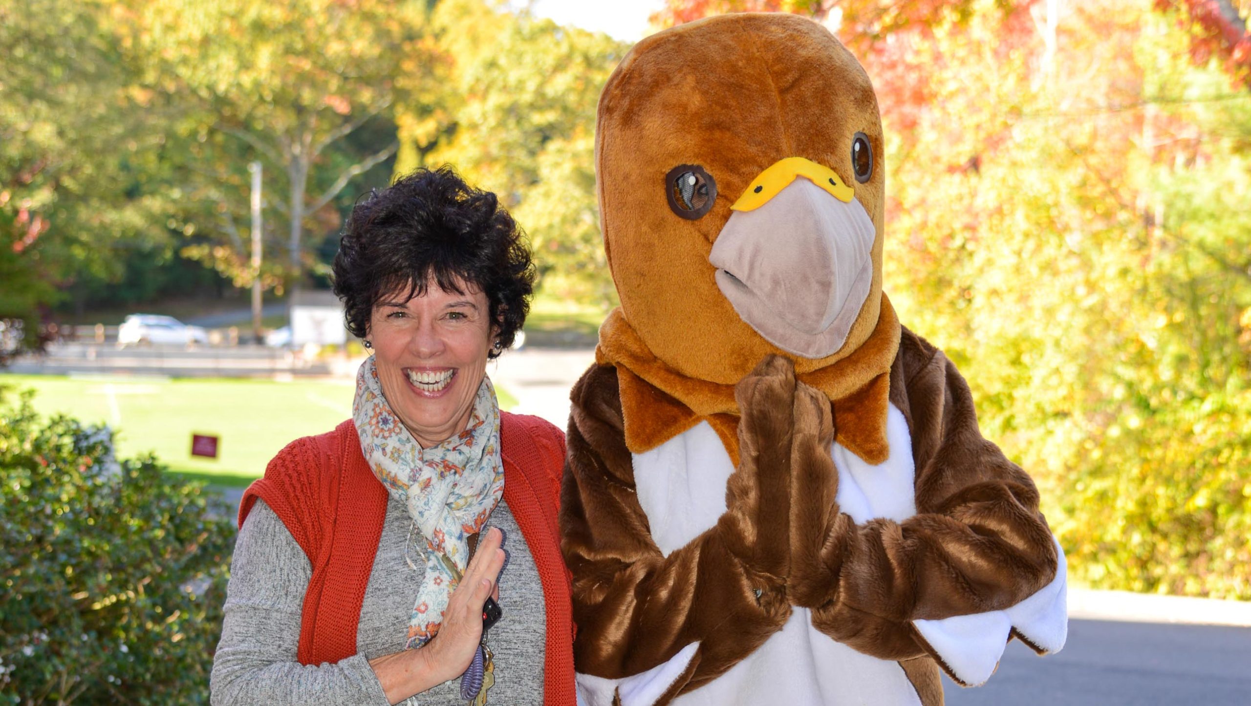 A teacher posing with the hawk mascot