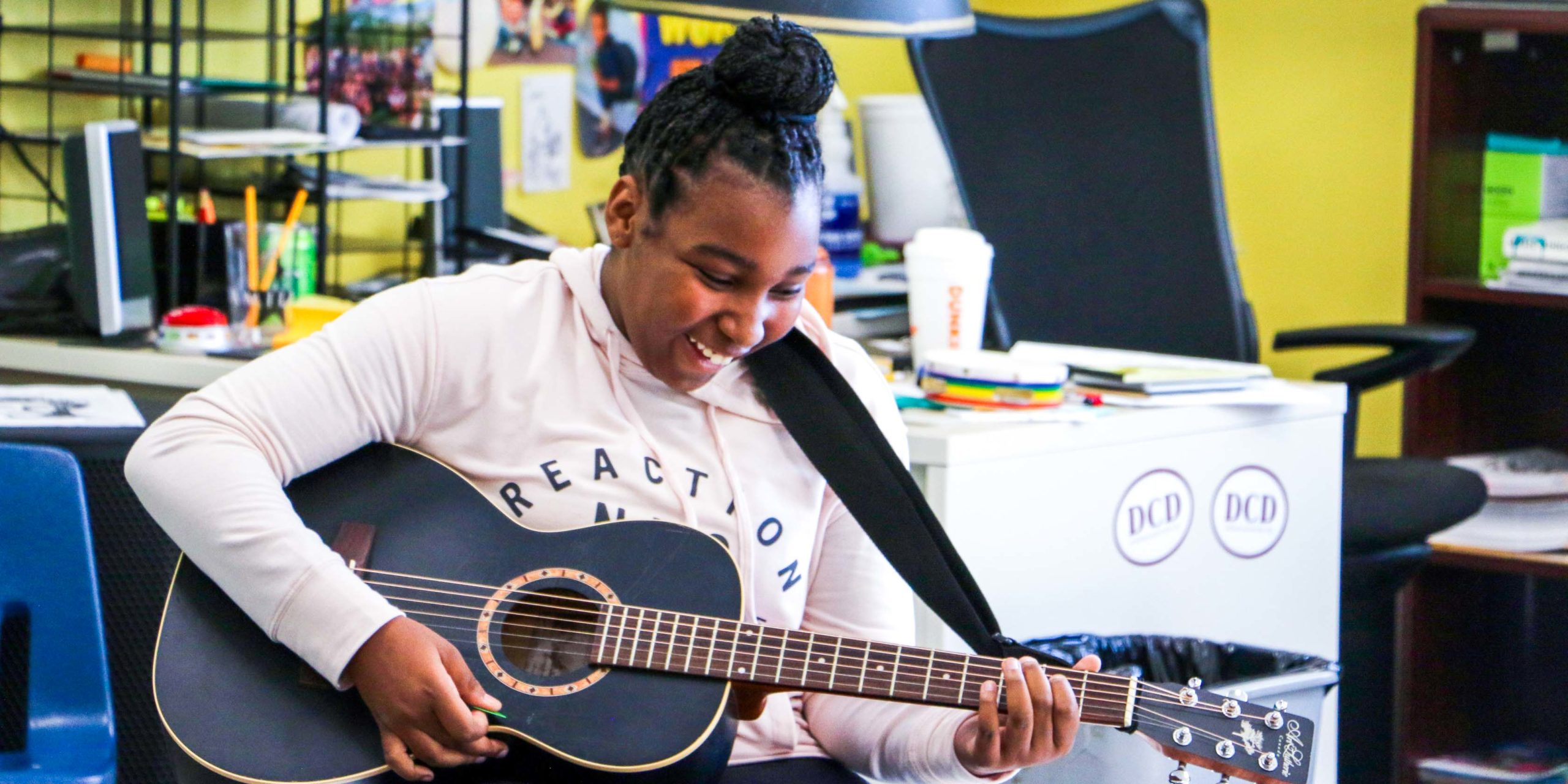 A student playing the guitar and smiling