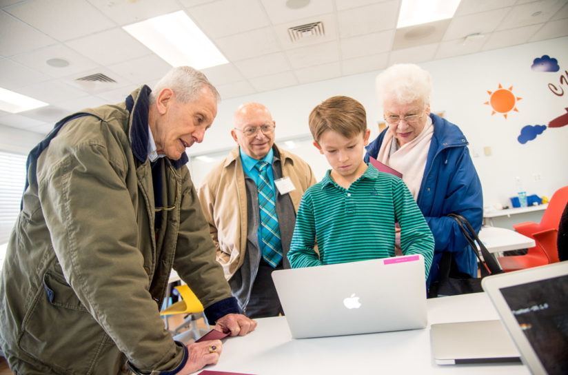 Grandparents watching a student use the computer