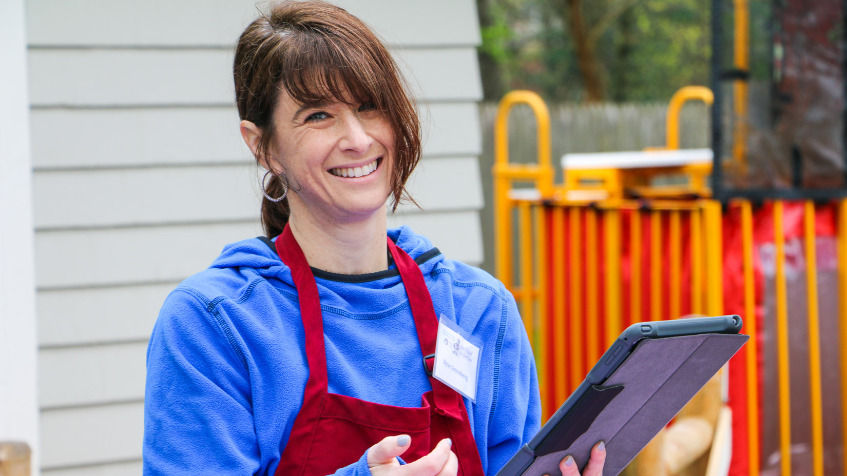 A parent smiling at the camera while volunteering