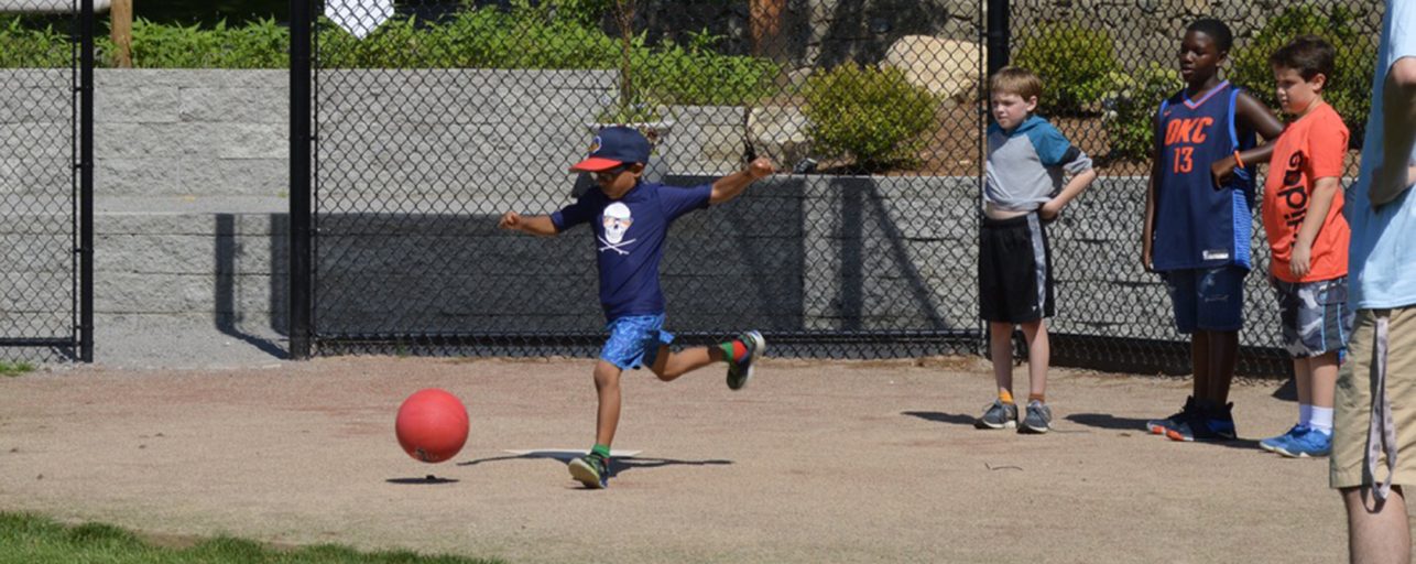 Boy kicking a ball playing kickball
