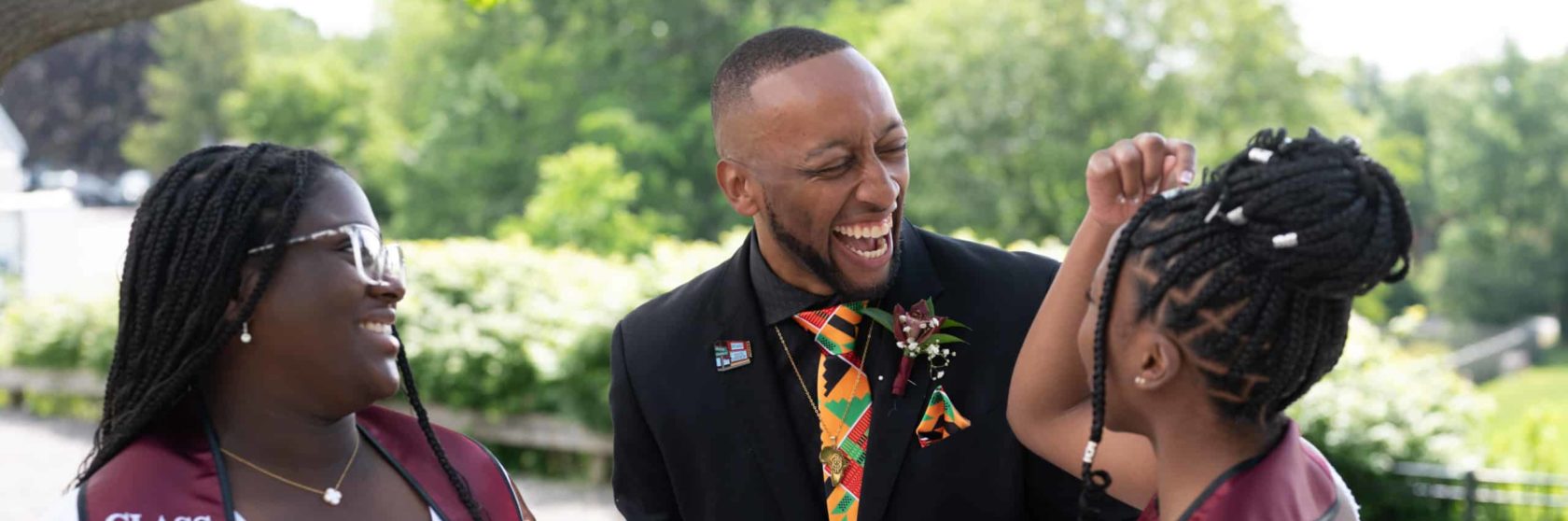 An advisor laughs with students at graduation.