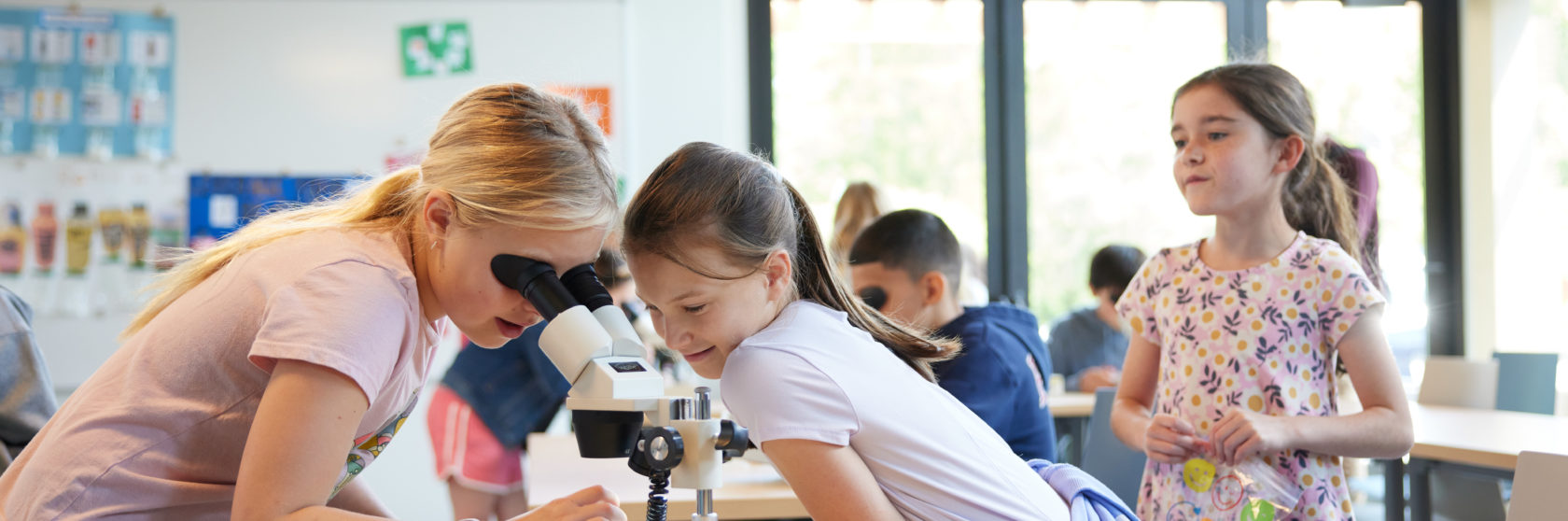 Students gather to examine a microscope.