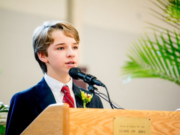 A student speaking at a podium at graduation.