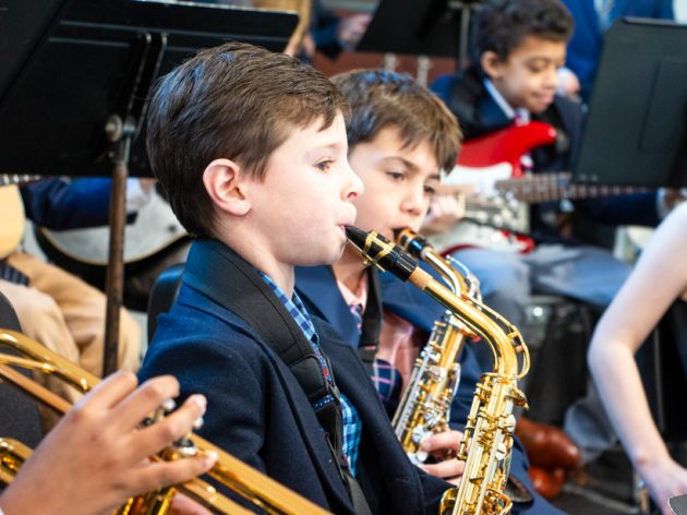 A student playing the saxophone in a band.