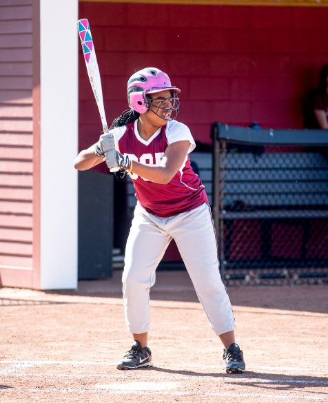 A student standing at home base ready to play softball.