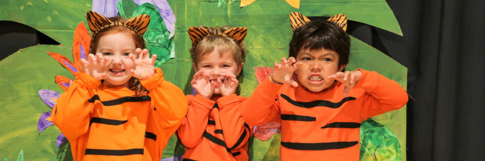 A group of children dressed as tigers posing on stage.