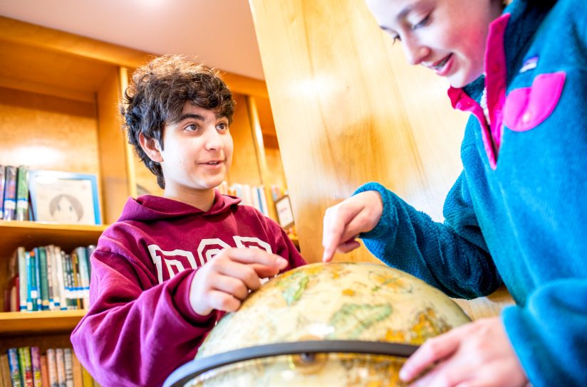 Two students examining a globe.