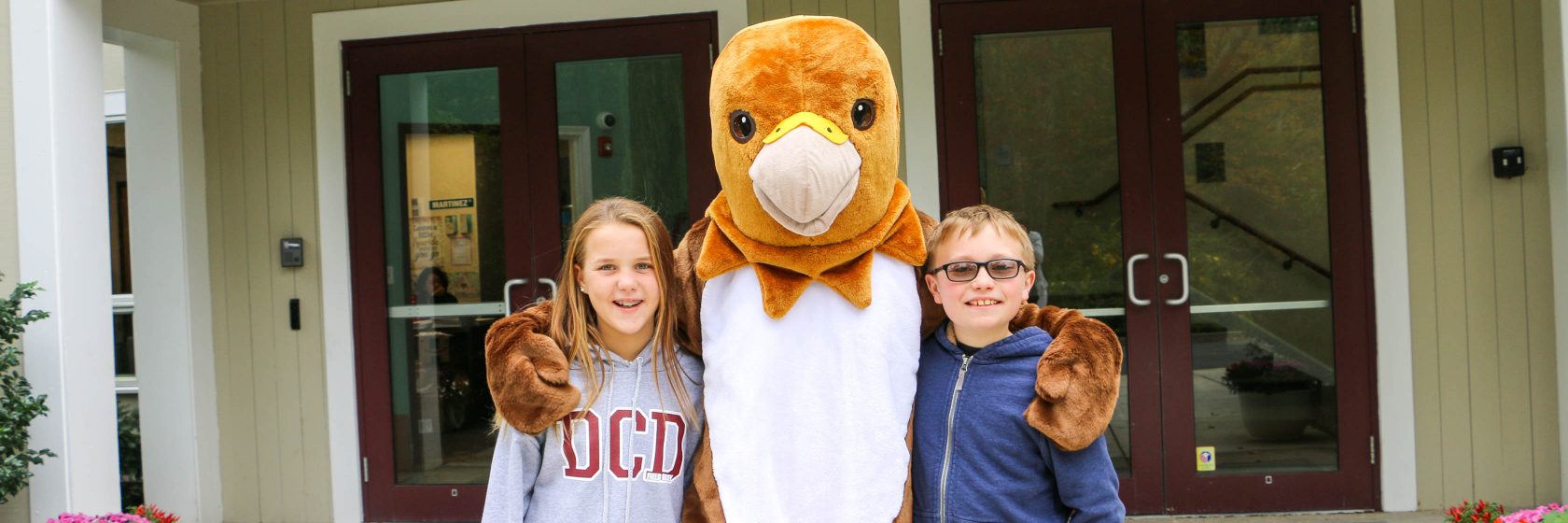 Hawk scholarship recipients posing with the hawk mascot in front of the school.