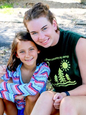 A camper and a counselor posing and smiling together.