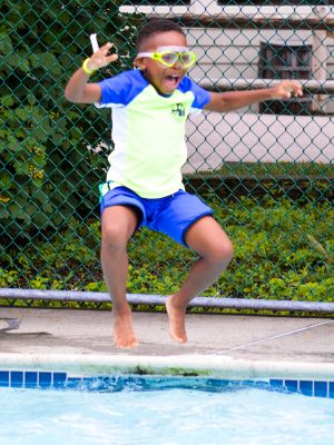 A young camper jumping into the pool.