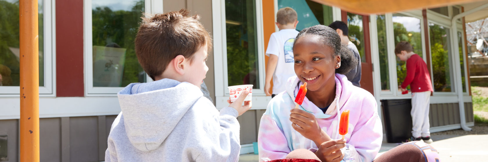 A kindergartener and eighth grader spend time together at recess.