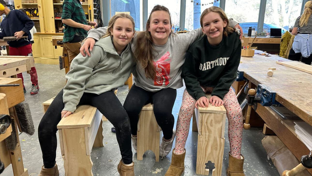 three girls sitting on benches made in the woodshop