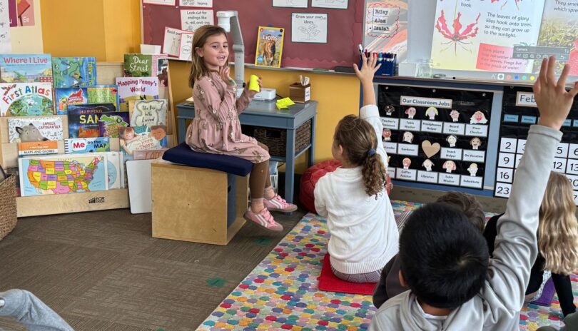 Children in classroom raising their hands and leading class