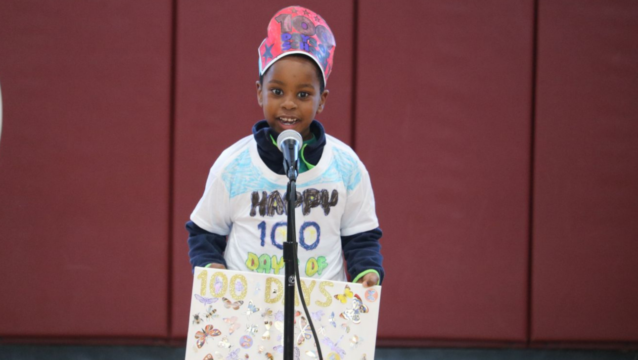 Boy holding a poster speaking into a micorphone